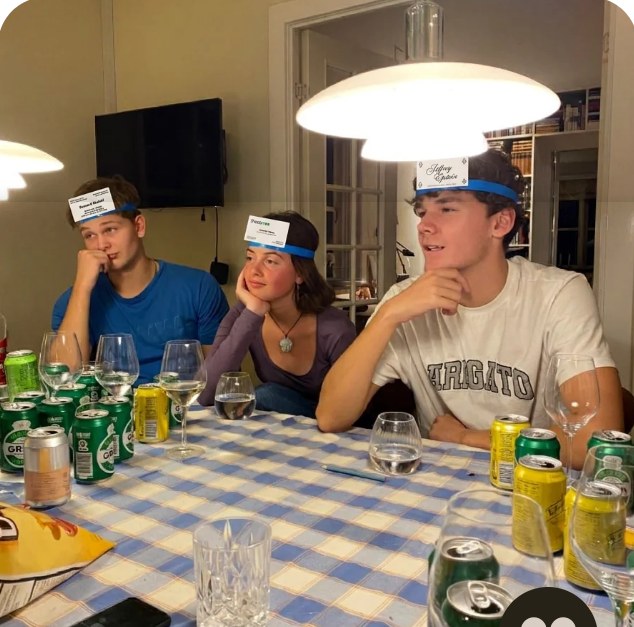Three friends at a table with cards on their foreheads
